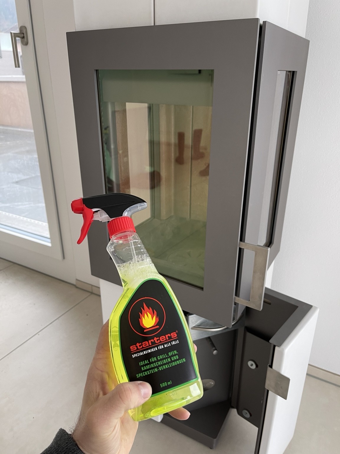 Kaminofen mit geöffneter Glastür und Spezialreiniger für die Kaminreinigung