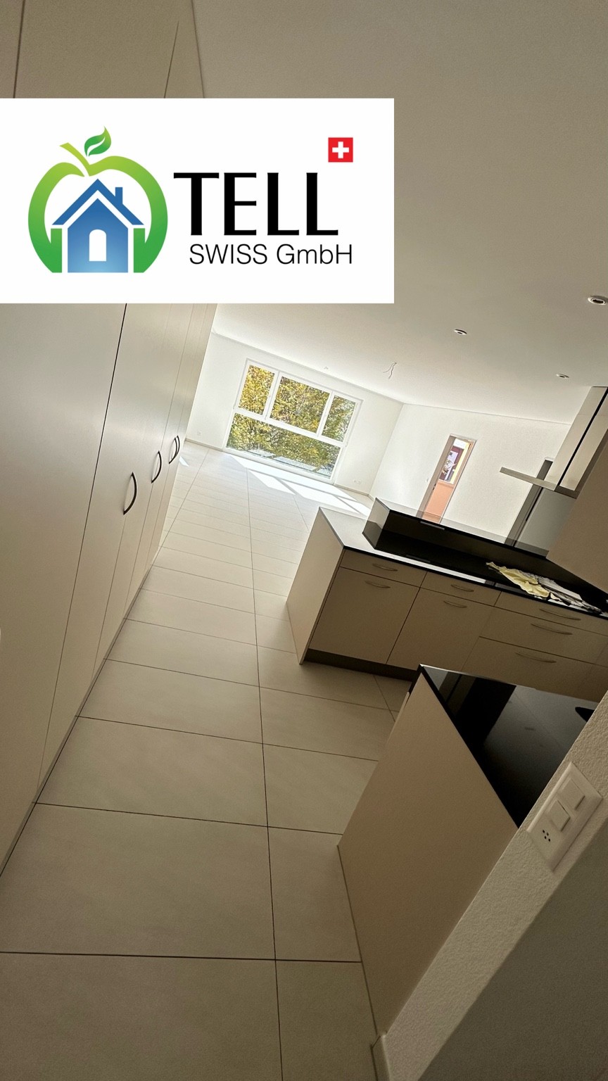 Umzugsreinigung einer leeren Wohnung mit offener Küche, Plattenboden und Tell Swiss Logo